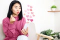 Asian woman using mobile phone dating online making hand sign mini heart flirting with her distance lover Royalty Free Stock Photo