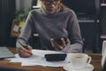 Asian woman using mobile phone and write to work online and report data tax. Season to pay tax, Accountant wear glasses calculate