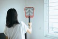 Asian woman using mosquito swatter at home,Female with mosquito electric net racket in bedroom Royalty Free Stock Photo