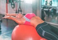 Woman using orange fitness ball to stretch her back and exercise her abs in fitness gym workout room Royalty Free Stock Photo