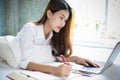 Asian woman is using a pen to write notes in her notebook and she uses a notebook to work on her bed at home Royalty Free Stock Photo