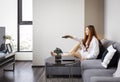 Asian woman using remote control to change channel while relaxingly watching television at home on the comfy sofa couch during Royalty Free Stock Photo