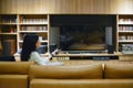 Asian woman using a remote control to turn on TV with blank screen