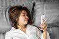 Asian woman using smart phone lying down in bed ,social addiction concept