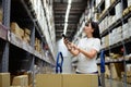 Asian woman using smartphone checking products in a furniture warehouse Royalty Free Stock Photo