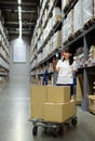 Asian woman using smartphone checking products in warehouse Royalty Free Stock Photo