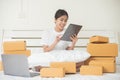 An Asian woman is using a tablet and a computer to happily find and choose products in her bed at home