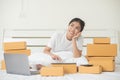 An Asian woman is using a tablet and a computer to happily find and choose products in her bed at home.