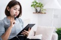 Asian woman using a tablet to write down ideas for work, planning, and studying online at home , Royalty Free Stock Photo