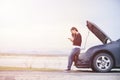 Asian woman is using a telephone to call the car mechanic. For fixing damaged cars on the road