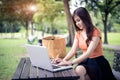 Asian woman using and typing on laptop keyboard in outdoors park. Woman chatting to her friends on social network. People and Royalty Free Stock Photo