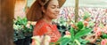 Asian woman in Vietnamese straw hat is smiling enjoying of her garden