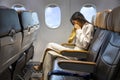 Asian woman is vomitting in the airplane during the flight using vomit bag due to the motion and travel sickness that cause dizzy