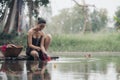 asian woman waering salong sitting on wooden bridge washing clothes in the river Royalty Free Stock Photo