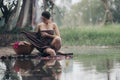 asian woman waering salong sitting on wooden bridge washing clothes in the river Royalty Free Stock Photo