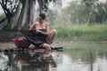 asian woman waering salong sitting on wooden bridge washing clothes in the river Royalty Free Stock Photo