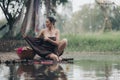 asian woman waering salong sitting on wooden bridge washing clothes in the river Royalty Free Stock Photo