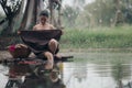 asian woman waering salong sitting on wooden bridge washing clothes in the river Royalty Free Stock Photo