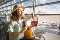 Asian woman waiting for her airplane in airport with passport and baggage. Vacation and journey concept Royalty Free Stock Photo