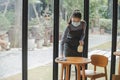 Asian woman waitress staff wearing protection face mask in apron cleaning table with disinfectant spray for protect infection coro Royalty Free Stock Photo