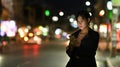 Asian woman waits for her private taxi by using a transportation app on the night street