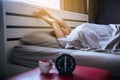 Asian woman wake up stretch oneself and yawn on her bedroom with blur black alarm clock