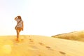 Asian woman walking on desert with many footprint on the sand with sunlight flare