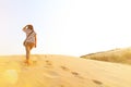 Asian woman walking on desert with many footprint on the sand with sunlight flare and copy space at UbonRatchaThani, Thailand