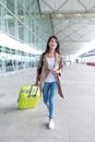 Asian Woman walking with luggage and holding cellphone in intern Royalty Free Stock Photo