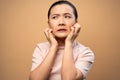 Asian woman was sick with irritate itching her skin standing isolated on beige background