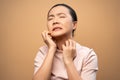 Asian woman was sick with irritate itching her skin standing isolated on beige background