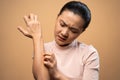 Asian woman was sick with irritate itching her skin standing isolated on beige background