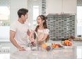 Asian woman washing fruit in the sink and handsome man standing next to her