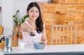 Asian woman wathcing tv on demand and use remote control change television channel at breakfast in morning Royalty Free Stock Photo