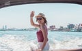 Asian woman waving her hand while sitting on boat