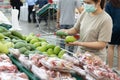 Asian woman wear a face mask,chooses necessary food,mango,fruit while shopping at supermarket,people panic buying, hoarding during