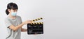 Asian woman wear face mask and hand`s holding black clapper board or movie slate or clapboard use in video production ,film, Royalty Free Stock Photo