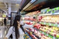 Asian woman wear face mask push shopping cart in suppermarket departmentstore. Girl, looking grocery to buy  fruit. Women wearing Royalty Free Stock Photo