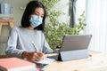 Asian woman wear medical mask while sitting learning online with laptop computer at home, concept online learning at home