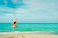 Asian woman wear swimwear and hat swing the swings at sand beach and looking beautiful tropical paradise sea and sky on sunny day Royalty Free Stock Photo