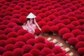 Asian woman wearing ao dai dress with Incense sticks drying outdoor in Hanoi, Vietnam