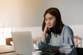Asian woman Wearing a blue striped shirt sitting in front of a laptop computer Take her hands, feet, chin With the expression Royalty Free Stock Photo