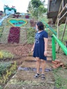 An Asian woman wearing a dark blue dress is taking a photo at a playground.