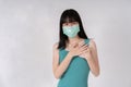 Asian woman wearing disposable protective mask with hands on heart