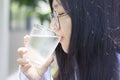 Asian women wearing eyesglasses drinking big glass drinking water at home in hot summer day