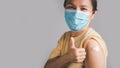 Asian woman wearing face mask with a smile on his face showing his vaccinated arm. vaccination, recommended inoculation concept