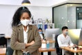 Asian woman wearing face mask smile and looking at camera working in new normal office and doing social distancing during corona v