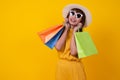 Asian woman wearing a hat and sunglasses holding a shopping bag happily on a bright yellow background.Shopping ideas Royalty Free Stock Photo
