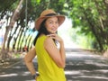 Asian woman wearing hat and yellow sleeveless standing middle of the road
