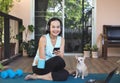 Asian woman wearing headphones, holding coffee cup, using mobile phone, sitting  on yoga mat in balcony  with computer laptop Royalty Free Stock Photo